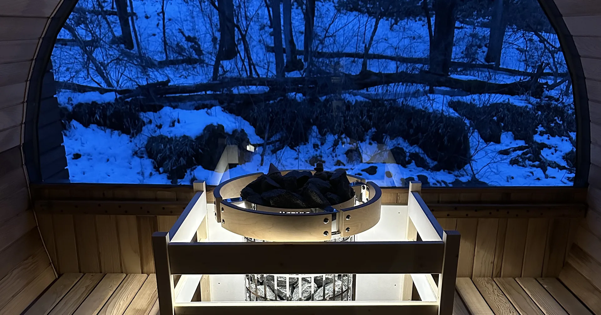 夜のサウナ窓越しに浮かぶ雪景色とライトアップされたヒーター