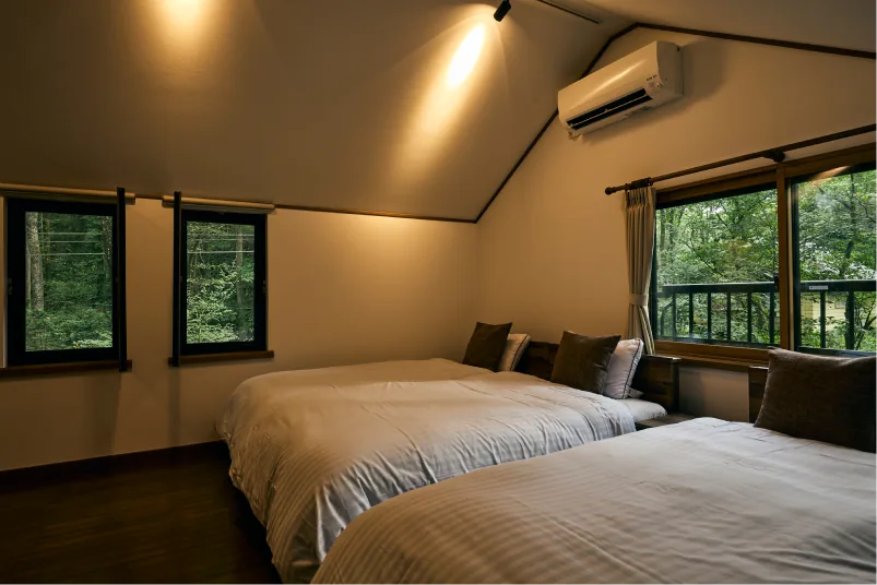 窓から緑がのぞく山小屋風の寝室